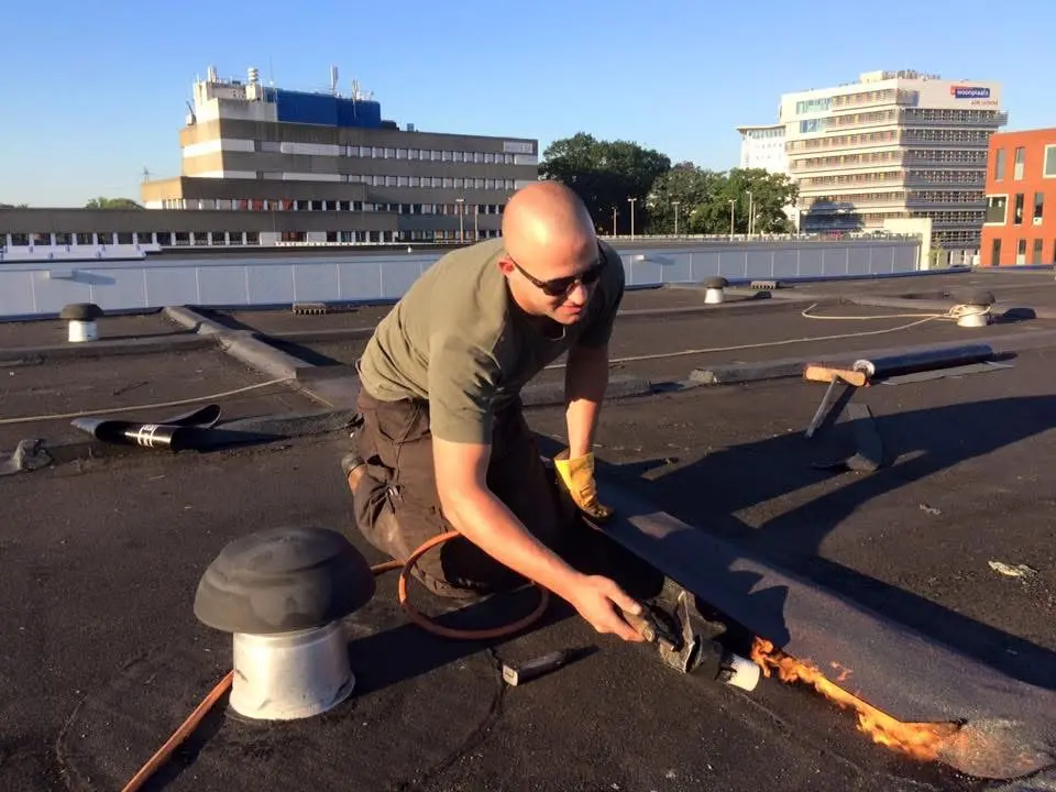 Ervaren dakdekker van Manig aan het werk op een plat dak